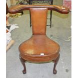 A GEORGE II STYLE HIDE COVERED READING CHAIR, with padded elbow rests and padded back, with pull out