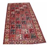 AN IRON RED AND IVORY GROUND HERIZ RUG,
with four rows of square panels, inside an ivory border,