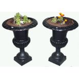 A PAIR OF HEAVY CAST IRON GARDEN URNS, 
each with a tongue and dart cast rim and a half reeded body,