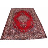 A  LARGE BURGUNDY GROUND PERSIAN CARPET,  
with blue and fawn floral medallion,