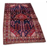 A HAMADAN RUG, 
with iron red medallion on a navy field, inside a triple border,