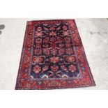 A HAMADAN RUG, 
the dark blue field with geometric designs, inside a burgundy border,