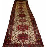A KARAJA RUNNER, 
the ivory ground with various shaped medallions, inside a burgundy ground border,