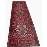 A BURGUNDY GROUND PERSIAN RUNNER, 
with three large and two small medallions,