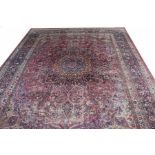 A LARGE SEMI ANTIQUE MESHED CARPET, 
with large central medallion, on an iron red,