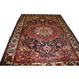 A LARGE BAKHTIARI RUG, 
the iron red and dark blue field with centre ivory medallion,