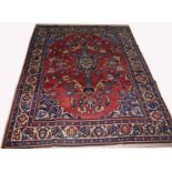 A PERSIAN RUG, 
the iron red field with a centre blue medallion, with stylised floral pattern,