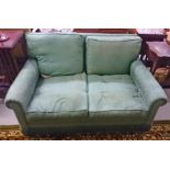 A TWO SEATER SETTEE COVERED IN GREEN FABRIC, 
modern with loose cushions.
