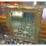 A VICTORIAN STYLE SWEPT GILT AND GESSO WALL MIRROR, 
with bevelled plate,