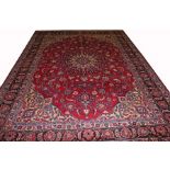 A PERSIAN MASHAD CARPET, 
with floral shaped centre ivory medallion, on a burgundy floral field,