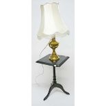 A BRASS OIL LAMP, 
converted to electricity; together with a tri-pod table.
