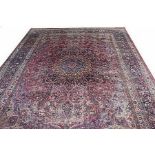 A LARGE SEMI-ANTIQUE MESHED CARPET, 
with large central medallion, on an iron red,