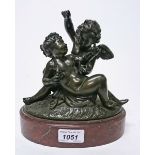 A 19TH CENTURY BRONZE GROUP,
modelled with two frolicking cherubs, on an oval rouge marble base,