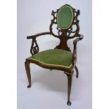 AN EDWARDIAN WALNUT ARMCHAIR, 
the scroll and leaf carved back, with an oval padded panel ,