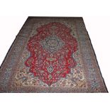 A TABRIZ CARPET, 
with cruciform navy floral medallion, on a burgundy floral field,