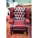 A LIBRARY WING ARMCHAIR, 
with button back and cushion seat, raised on four cabriole legs,