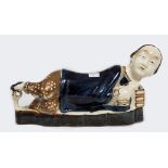 A CHINESE GLAZED STONEWARE PILLOW, 
modelled as a reclining woman, in blue , cream and tan,