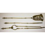 A SET OF THREE HEAVY BRASS FIRE IRONS, 
comprising shovel with pierced pan, poker and tongs,