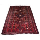 AN AFGHAN RUG, 
with three large diamond medallions, on an iron red ground with stylized flowers,