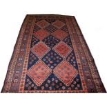 A SHIRAZ RUG, 
with two rows of diamond medallions in iron red, on a dark blue ground,