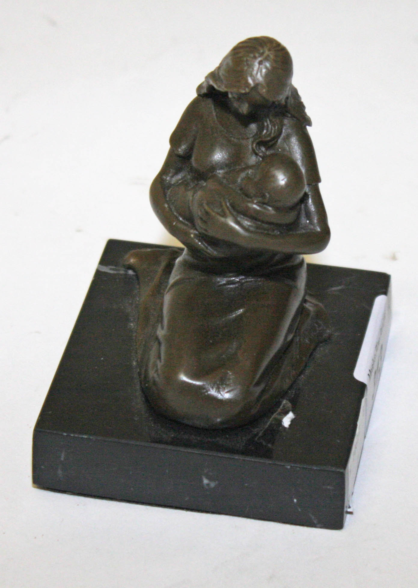 A SMALL BRONZE GROUP, 
modelled as a mother and infant on black marble base, 4.5in (11.5cm).