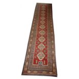 AN ATTRACTIVE ORIENTAL RUNNER, 
with a row of eleven octagons on iron red ground,