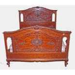 AN EDWARDIAN CARVED MAHOGANY BEDSTEAD, 
the arched and moulded back with a leaf scroll crest,