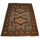 A TURQUOISE AND RED GROUND RUG, 
with two medallions inside a triple band border,
