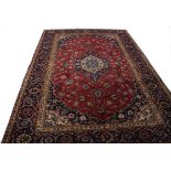 AN OLD KASHAN RUG, 
iron red ground with a centre ivory and navy blue floral central medallion,