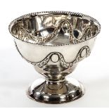 AN IRISH EMBOSSED SILVER STEM BOWL, 
Dublin 1905 with leaf swags under a bead hammered edge,