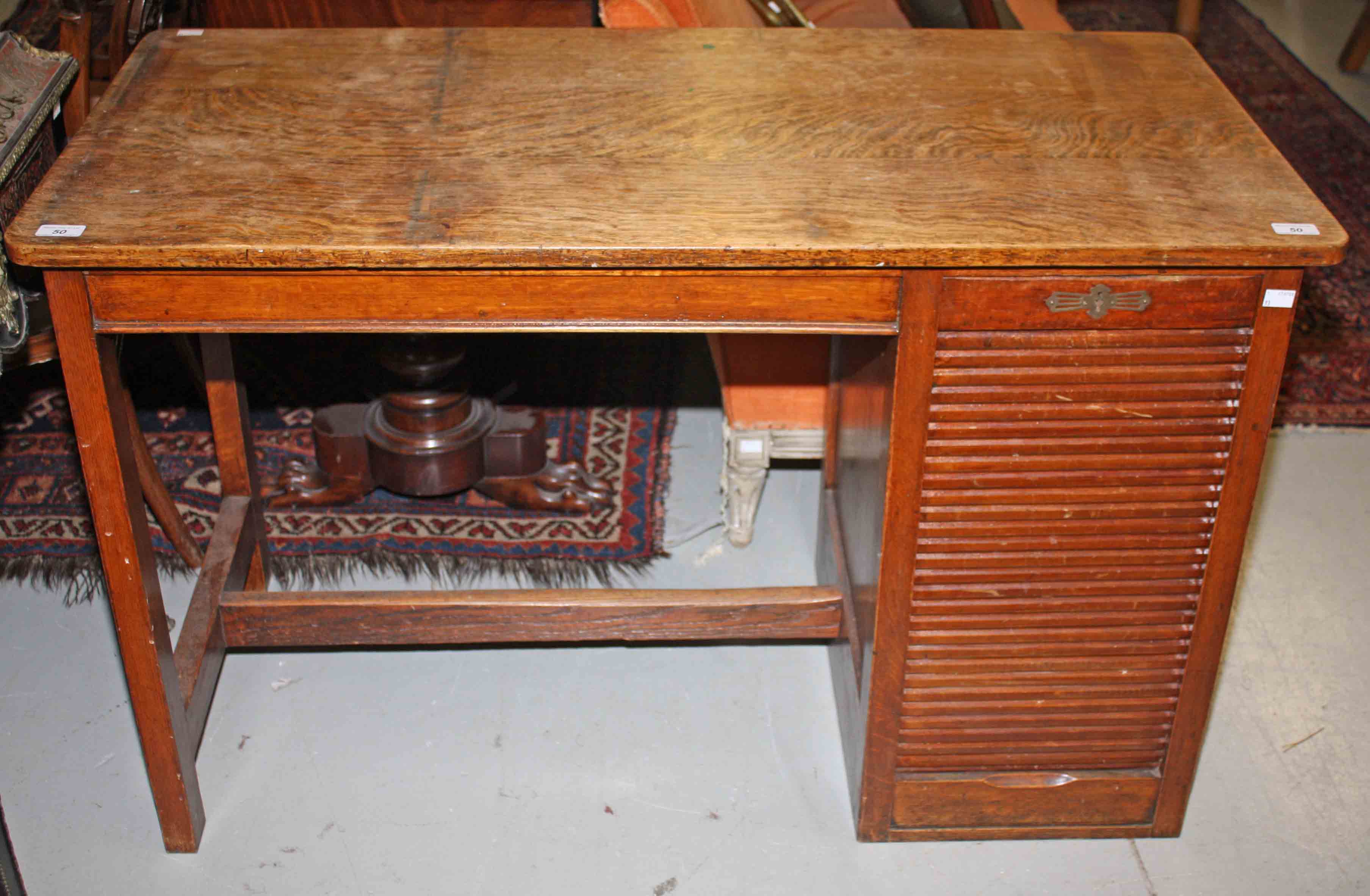 A SINGLE PEDESTAL OAK DESK, 
with rectangular top, above a tambour fronted pedestal, 45in (114cm)w.