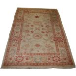 AN ORIENTAL IVORY GROUND RUG, 
with stylised flowers inside a conforming border with two red bands,