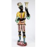 A DECORATED TERRACOTTA FIGURE, 
modelled as a Blackamoor figure holding a rustic cornucopia,