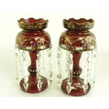 A PAIR OF LATE 19TH CENTURY RUBY GLASS LUSTRES WITH ENAMELLED AND GILT DECORATION AND PRISMATIC