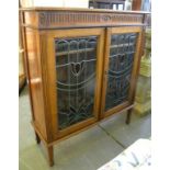 AN EDWARDIAN WALNUT BOOKCASE WITH COLOURED AND LEADED GLASS DOORS