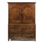 A WELSH OAK PRESS CUPBOARD the upper part with cavetto cornice and enclosed by a pair of ogee arch