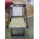 A VICTORIAN EBONISED AND GILT FOLDING CHAIR, THE CREST RAIL INSET WITH WEDGWOOD JASPER WARE