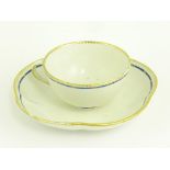 A CHELSEA DERBY LOBED TEACUP AND SAUCER WITH BLUE BORDER AND GILT DENTIL RIM