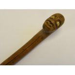 A CARVED WOOD WALKING CANE, THE HANDLE IN THE FORM OF A GROTESQUE HUMAN HEAD WITH BONE EYES, 19TH