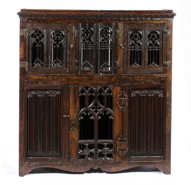 AN OAK AUMBRY, EARLY 16TH C AND LATER  with battlemented cornice and doors of gothic tracery or