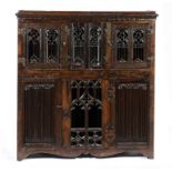 AN OAK AUMBRY, EARLY 16TH C AND LATER  with battlemented cornice and doors of gothic tracery or
