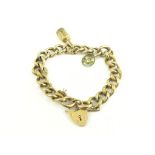 A GOLD CURB BRACELET, WITH PADLOCK AND MOUNTED WITH TWO CHARMS, 15G