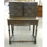 A VICTORIAN OAK SIDE TABLE SURMOUNTED BY A CABINET ENCLOSED BY GUILLOCHE CARVED DOORS