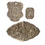 A CHINESE SILVER REPOUSSÉ DRAGON WAIST CLASP, A SIMILAR SHIELD SHAPED PLAQUE, POSSIBLY A BADGE AND A