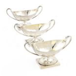 A SET OF THREE GEORGE III SILVER SALT CELLARS engraved with swags, crested, 14.5cm over handles,