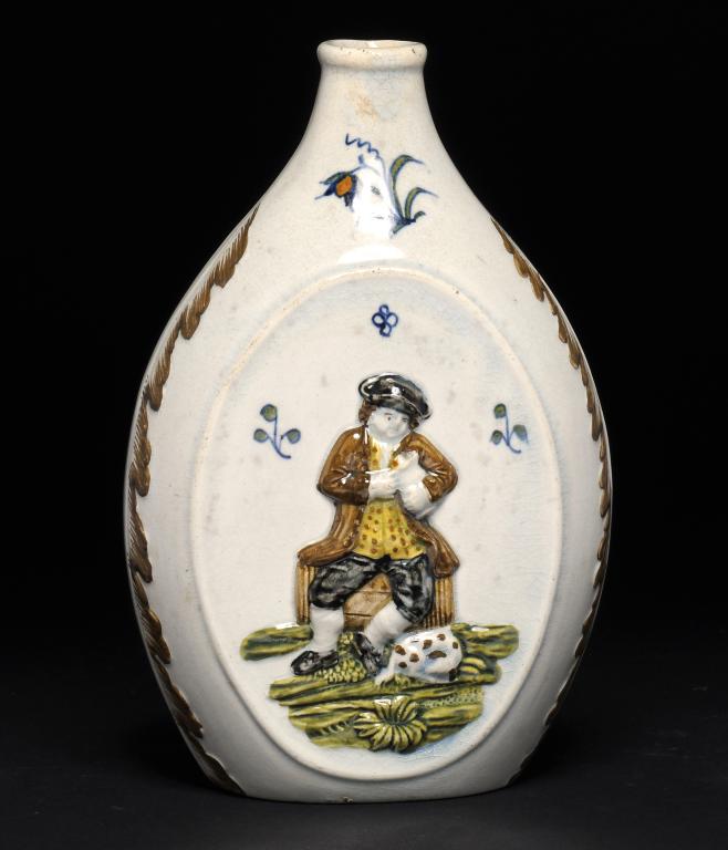 A PRATTWARE FLASK, C1810 moulded to either side with a man seated on a barrel, a glass and pipe or