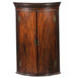 A GEORGE III MAHOGANY BOW FRONTED CORNER CUPBOARD, C1800 the green painted interior fitted with