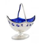 A GEORGE III SILVER NAVETTE SHAPED AND PIERCED SUGAR BASKET with swing handle, blue glass liner,