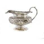 AN IRISH GEORGE IV SILVER CREAM JUG of melon shape, chased with flowers, crested, 11.5cm h, by