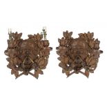 A PAIR OF CARVED OAK MASK WALL LIGHTS, EARLY 20TH C with two metal branches, 27cm h, stamped on iron